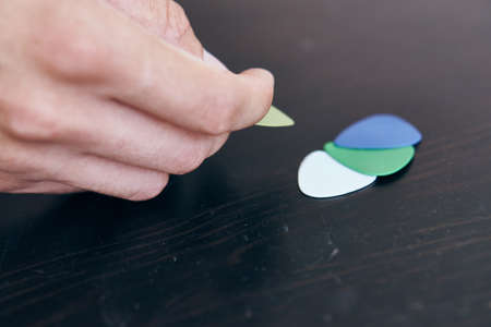 Hands, multi-colored mediators for the guitar lie on the table.の写真素材