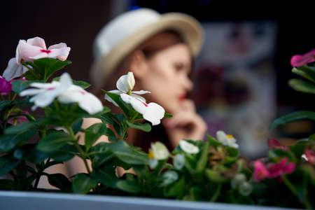Young beautiful woman sits in a cafe near the flowers.の写真素材