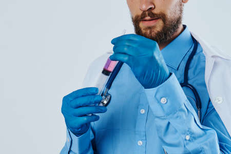 Man with a beard on a white isolated background holds medical instruments, medicine, doctor, syringe.の写真素材
