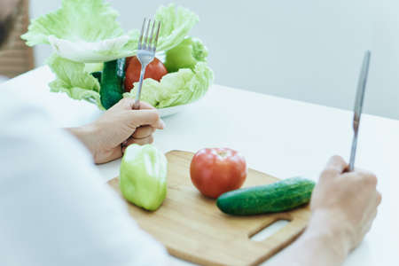 Man at the table on a white isolated background, vegetables, vegetarianism, diet.の写真素材