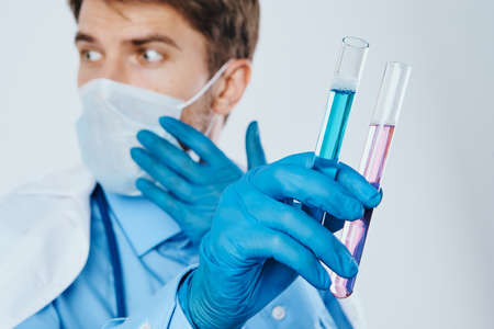 A man with a beard in a medical mask holds test tubes for experiments, science, a doctor, a scientist, medicine.の写真素材