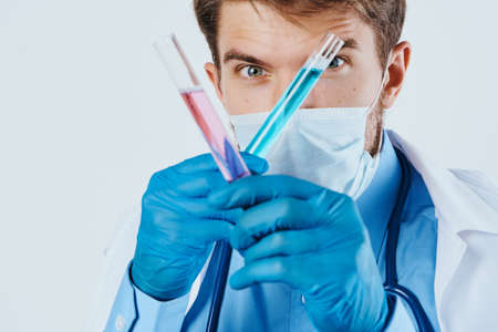 A man with a beard on a light background holds test tubes for experiments, science, scientist.の写真素材