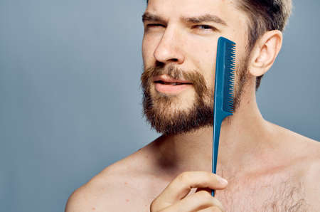 Man with a beard on a gray background holds a comb.の写真素材