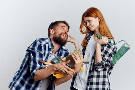 Young beautiful woman on white isolated background with a man with a beard holding stoic tools for repair.の写真素材