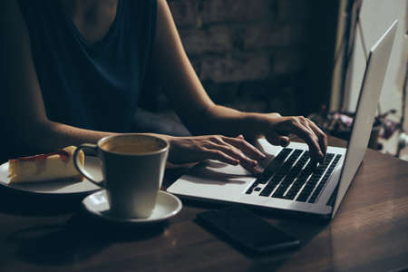 Woman working behind laptop in cafe, breakfast.の写真素材