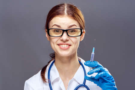 Young beautiful woman on a gray background in a medical dressing gown, doctor, medicine.の写真素材