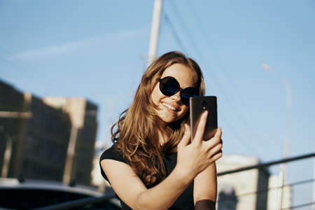 Young beautiful woman in sunglasses doing selfie outdoors in the city.の写真素材