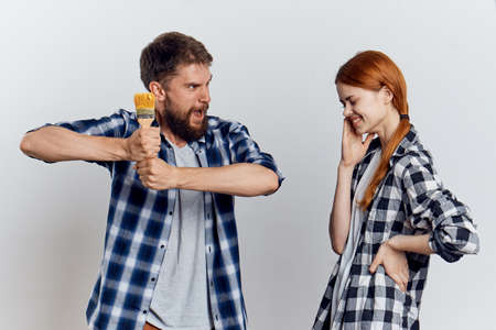 Young beautiful woman on a light background and a man with a beard holding construction tools for repair.の写真素材
