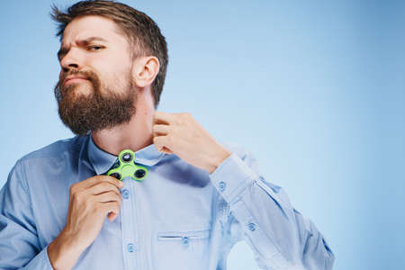 Man with a beard on a blue background holds a spinner, toy, entertainment.の写真素材