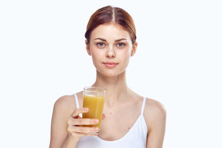 Young beautiful woman on white isolated background holds a glass of freshly squeezed juice, diet, fitness, slimming.の写真素材
