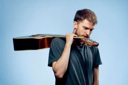 Man with a beard on a blue background holds a guitar, musical instruments.の写真素材