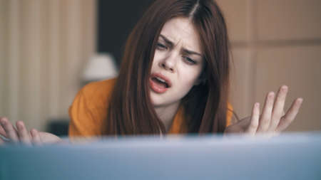 Indignant woman in bed looking at laptop.の写真素材