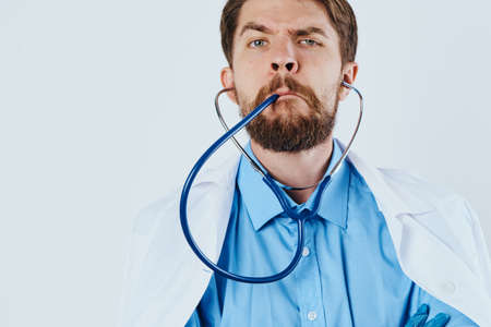 Man with a beard on a white isolated background holds a stethoscope, medicine, doctor.の写真素材