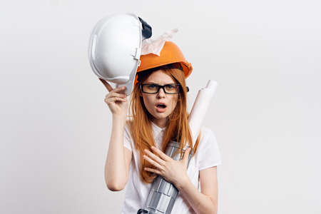 Builder woman in an orange helmet on a gray background.