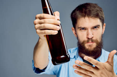A man with a beard on a gray background holds a bottle of beer, alcohol.の写真素材