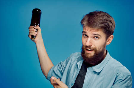 Man holding a bottle of beer on a blue background.の写真素材