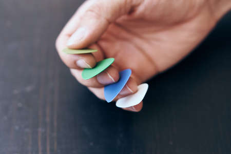 Hands, man holds multicolored picks for guitar.の写真素材