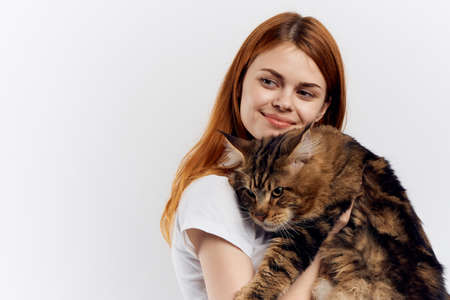Young beautiful woman on white isolated background holds a cat