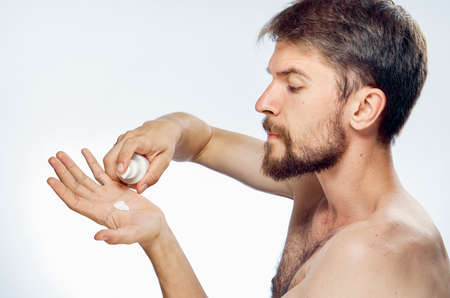 Man with a beard on white isolated background applies cosmetic cream on hand.の写真素材