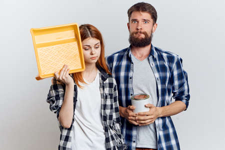 Man with a beard on a white isolated background with a beautiful woman holding construction tools for repair.の写真素材
