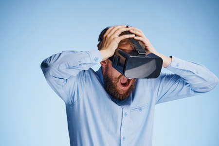 Man with a beard on a blue background with glasses of virtual reality, entertainment.