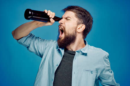 Man with a beard on a blue background drinking beer, alcohol.の写真素材