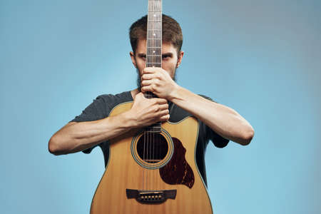 Man with a beard on a blue background holds a guitar, music, musical instruments.の写真素材