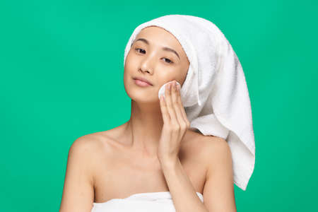 Beautiful young woman on a green background in a towel, asian, spa.の写真素材