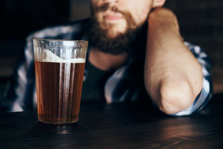 A man with a beard sits in a bar and drinks beer.の写真素材