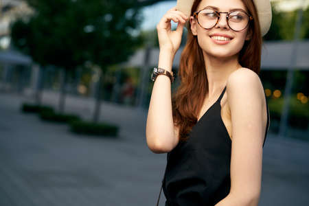 Beautiful young woman with glasses and beige hat on the street in the city.の写真素材