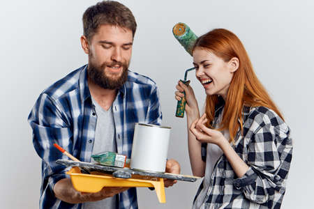 Beautiful young woman with a bearded man on a light background holding construction tools.の写真素材