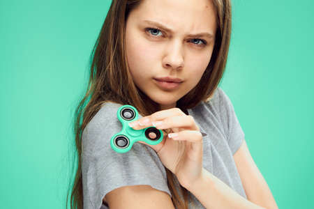 Beautiful young woman on a green background holds a spinnet spinner, toy.の写真素材