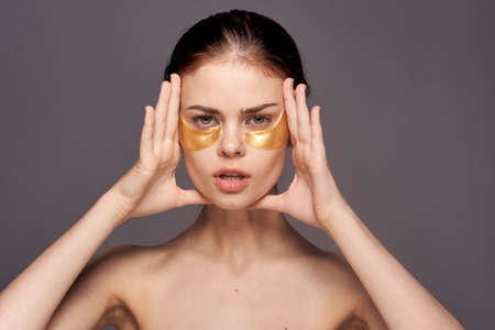 Young beautiful woman on a gray background, patches for the eyes, skin care, portrait, emotions.の写真素材