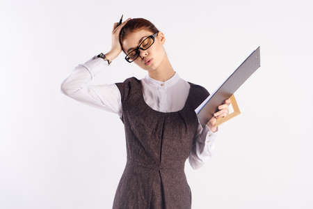 Young beautiful woman in glasses on white isolated background holds a folder with documents, teacher, study.の写真素材