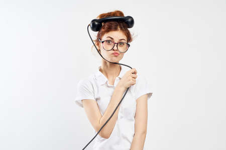 Young beautiful woman on white isolated background holds a fixed telephone receiver.の写真素材