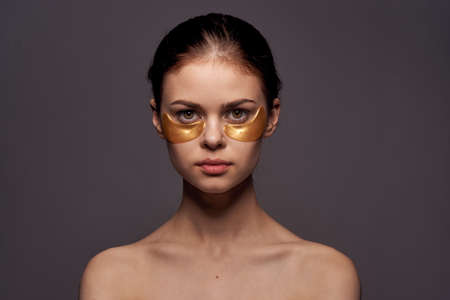 Young beautiful woman on a black background, eye skin care.