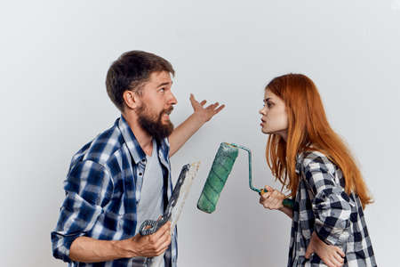 Man with a beard with a beautiful woman on a light background, conflict, tools for repairing.の写真素材