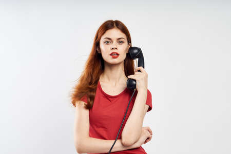 Beautiful young woman on a white background holds a fixed telephone, communication.の写真素材