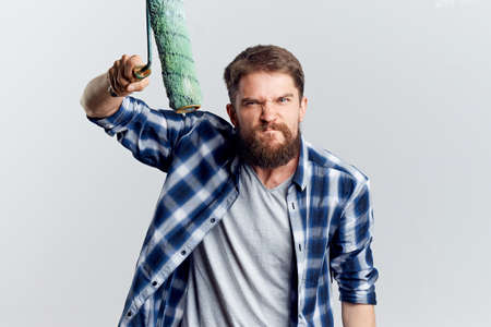 Man with a beard on a light background holds construction tools for repair, emotions, portrait.