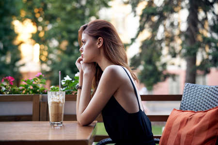 Young beautiful woman sitting at a table in a cafe on the street.の写真素材