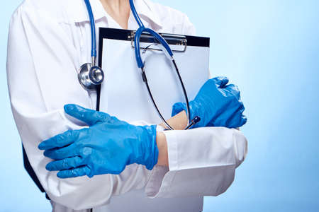 Woman doctor on blue background holds documents in medical dressing gown.