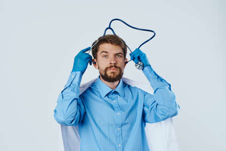Man with a beard against a light background in a medical dressing gown, doctor, medicine.