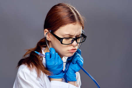 Young beautiful woman in glasses and in medical dressing gown on black background, portrait, doctor.