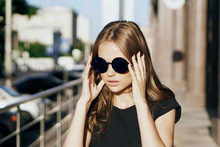 Young beautiful woman in round sunglasses in summer on the street.の写真素材