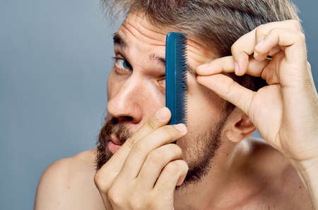 Man with a beard on a gray background combs his eyebrows, portrait.の写真素材