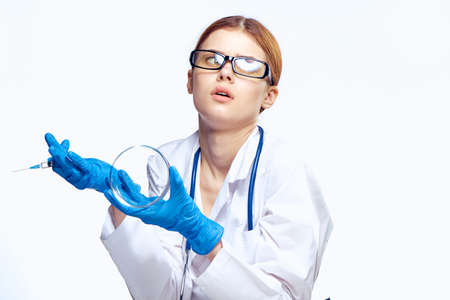 Young beautiful woman in glasses on white isolated background holds a petri dish, doctor, medicine, science.の写真素材