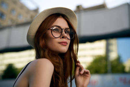 Young beautiful woman in a hat and wearing glasses on the street.の写真素材