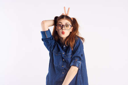 Girl teenager on a light background with glasses, emotions, fooling around.の写真素材