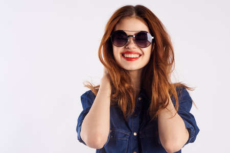 Young beautiful woman on a light background in sunglasses, portrait, smile, blank space for copy.