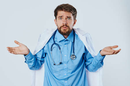 Man with a beard on a light background in a medical dressing gown, emotions, doctor, medicine.の写真素材
